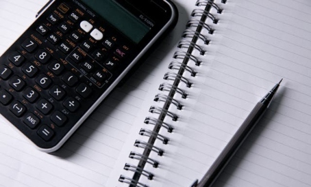 Cuaderno abierto con calculadora y lápiz encima