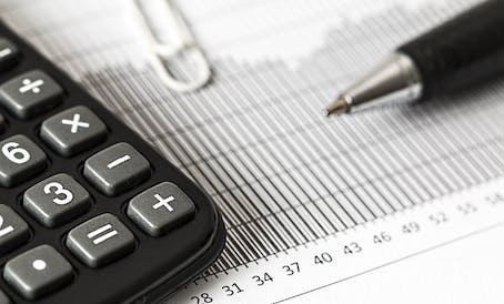 Calculadora, lápiz y clip sobre gráficos financieros de una empresa