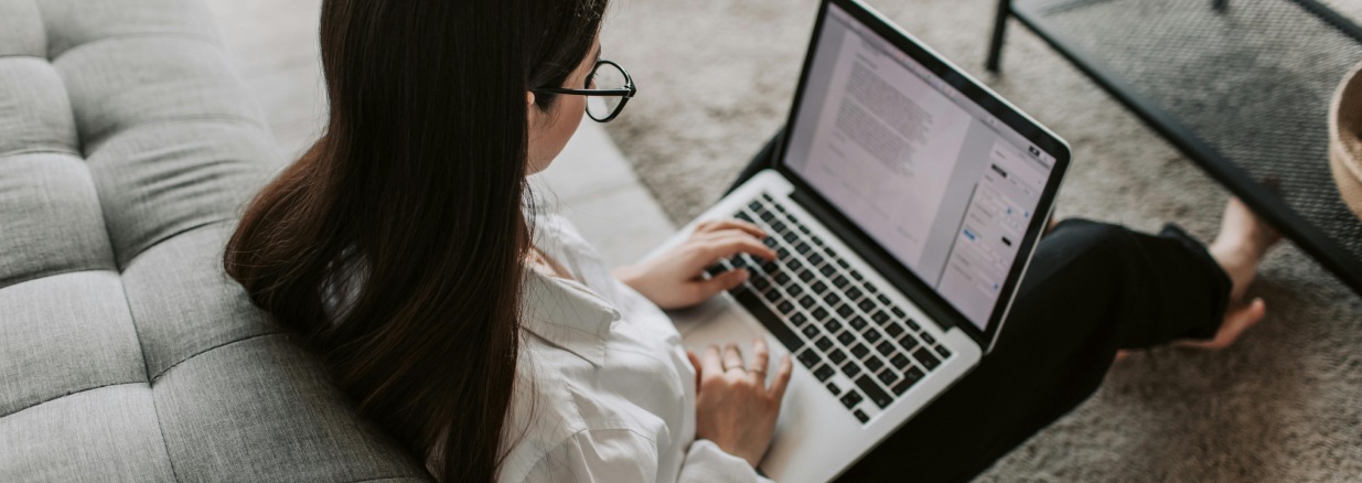 Mujer joven sentada en el living de su casa buscando en Internet cómo pedir un crédito para emprendimientos
