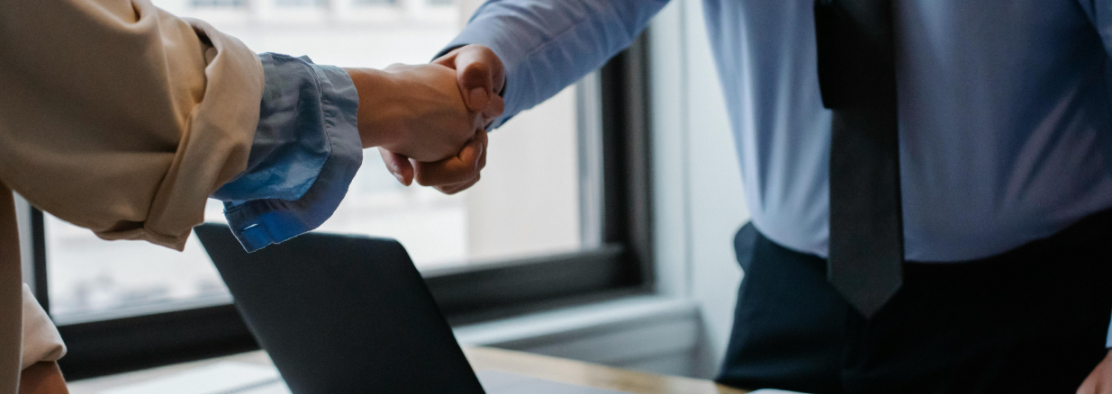 Emprendedora y ejecutivo de un banco estrechando las manos después de haber sido aprobado un sistema de financiamiento para pymes