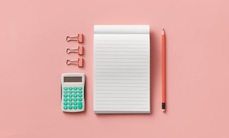 Calculadora, bloc de notas, un lápiz y clips encima de un escritorio